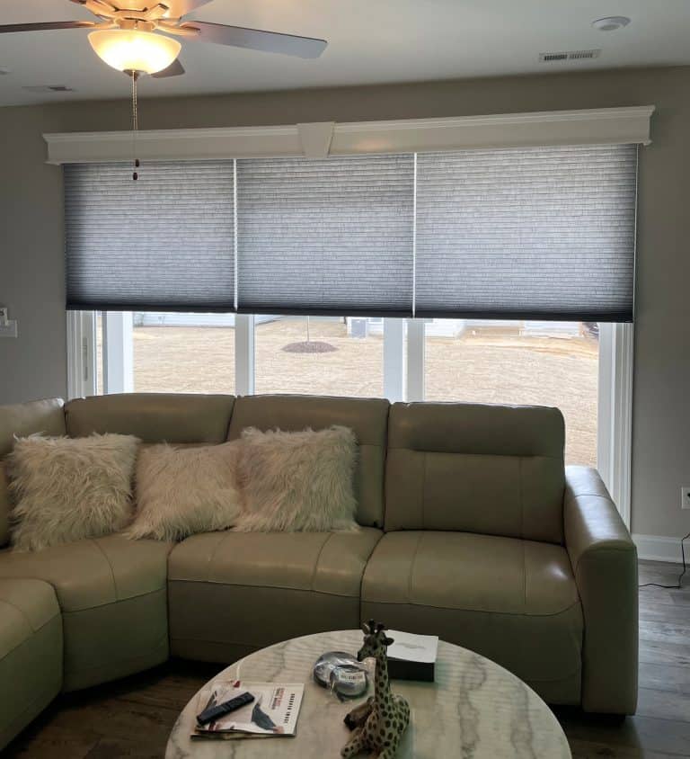 Motorized cellular shades with a wooden cornice board across the top to hide the shades.